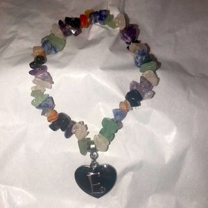 Cute stretch mineral rock bracelet with a black heart and the letter E on it.